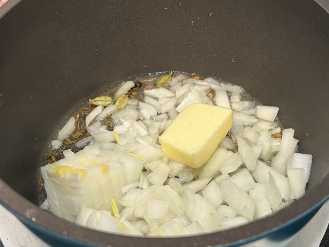 テンパリングスパイスが香ってきたら、玉ねぎとバターを加えて炒めます